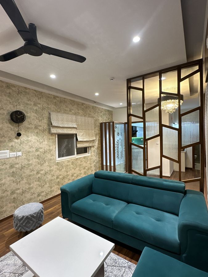 Living room with teal velvet sofa, fluted glass partition and chandelier